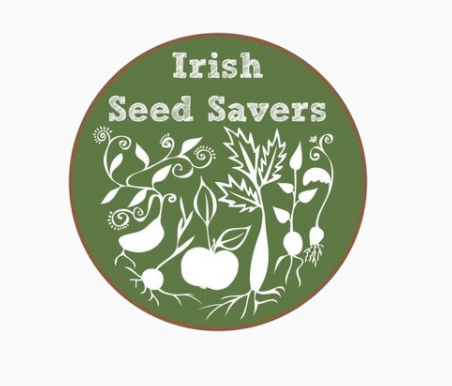 Green Circle with white text and images. The Text reads "Irish Seed Savers" and below are a variety of white vegetables 